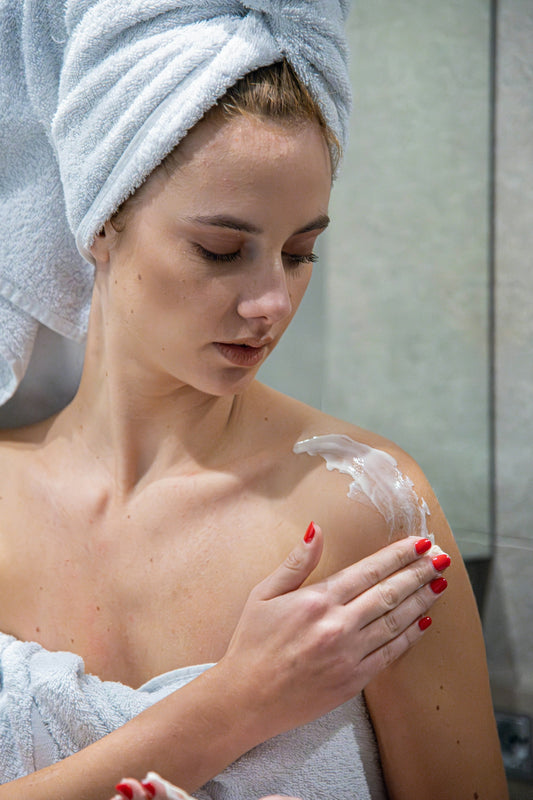 a woman with a towel on her head is shaving her face