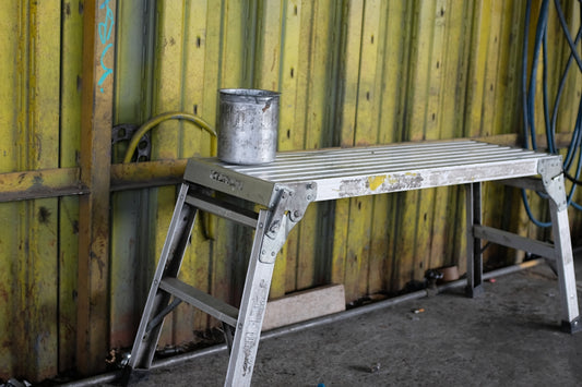 a metal step stool sitting next to a wooden wall