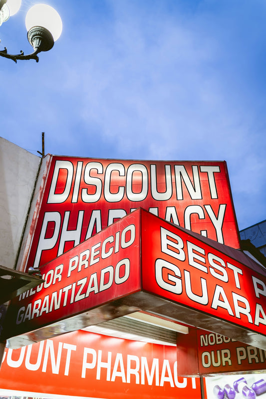 Discount pharmacy sign illuminated at dusk.